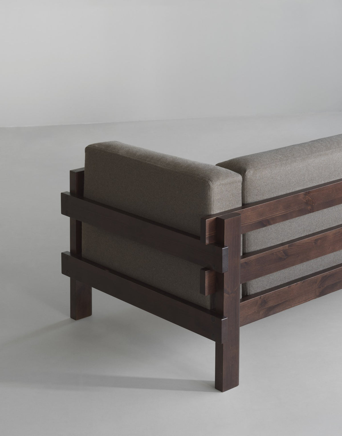 Kube 3er Sofa in Anthrazit von Normann Copenhagen mit sichtbarem Kiefernholz-Rahmen und lose aufliegenden Polsterkissen.