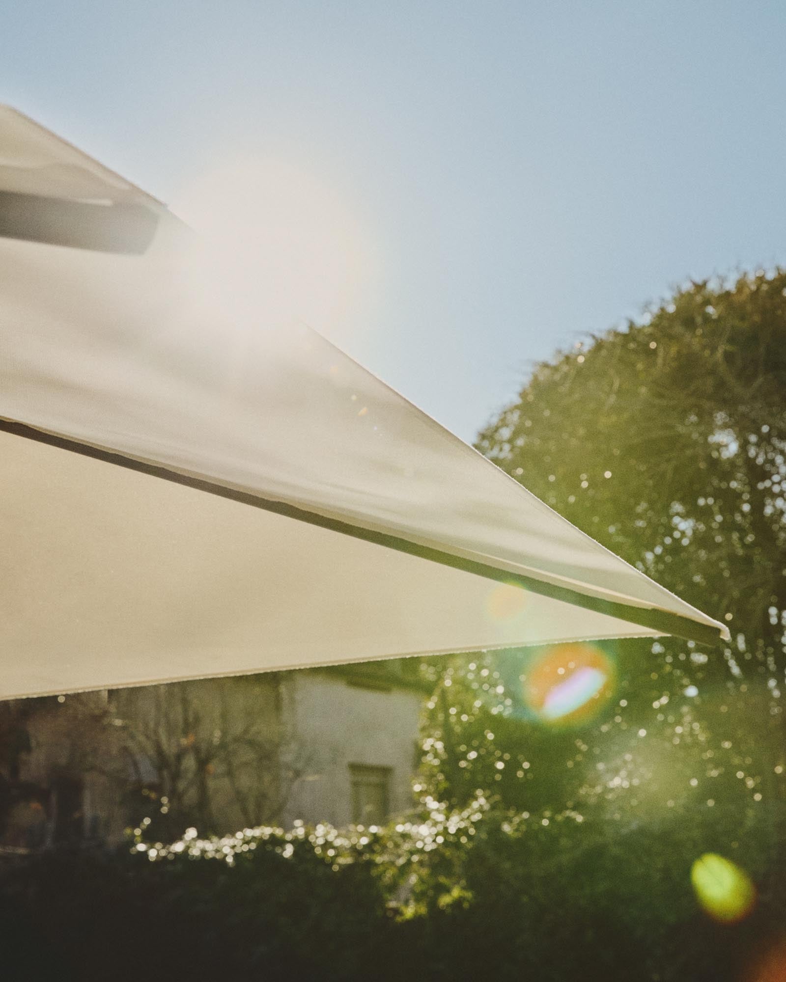 Exzentrischer Sonnenschirm Noli in warmem Beige, ausgestattet mit einem stabilen taupefarbenen Aluminiumgestell, perfekt für entspannte Sommertage im Freien.