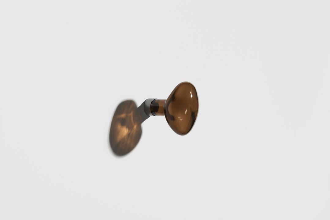 Kleiderhaken Bubble in Limette aus mundgeblasenem, lackiertem Glas mit rundem Blasen-Design und mattem Stahl-Befestigungssystem an weisser Wand.