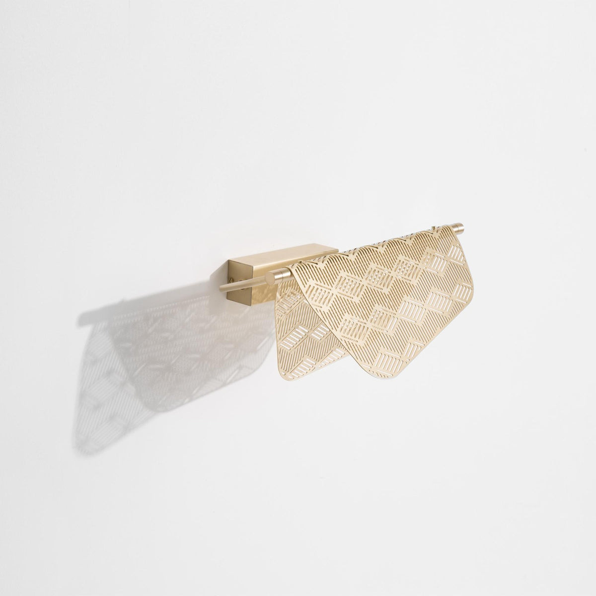 Wandlampe Mediterranea von Petite Friture aus gebürstetem Messing mit spitzenartiger, durchbrochener Struktur an heller Wand montiert.