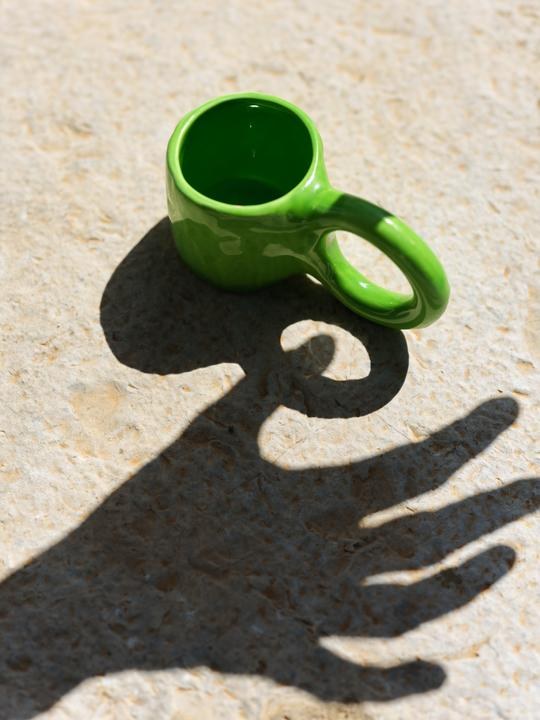 Keramiktasse Donut in Pistazie mit glasierter Oberfläche und donutförmigem Henkel, mittlere Grösse, handwerklicher Look, auf hellem Hintergrund.