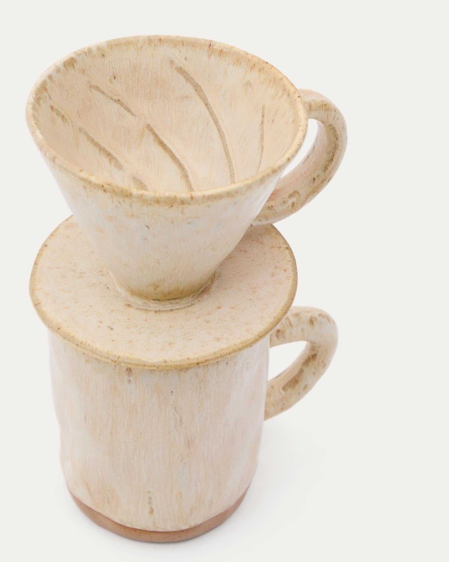 Erleben Sie das Set Zunel von Kave Home: Eine stilvolle Keramiktasse mit passendem Kaffeefilter in zeitlosem Beige für Kaffeeliebhaber.