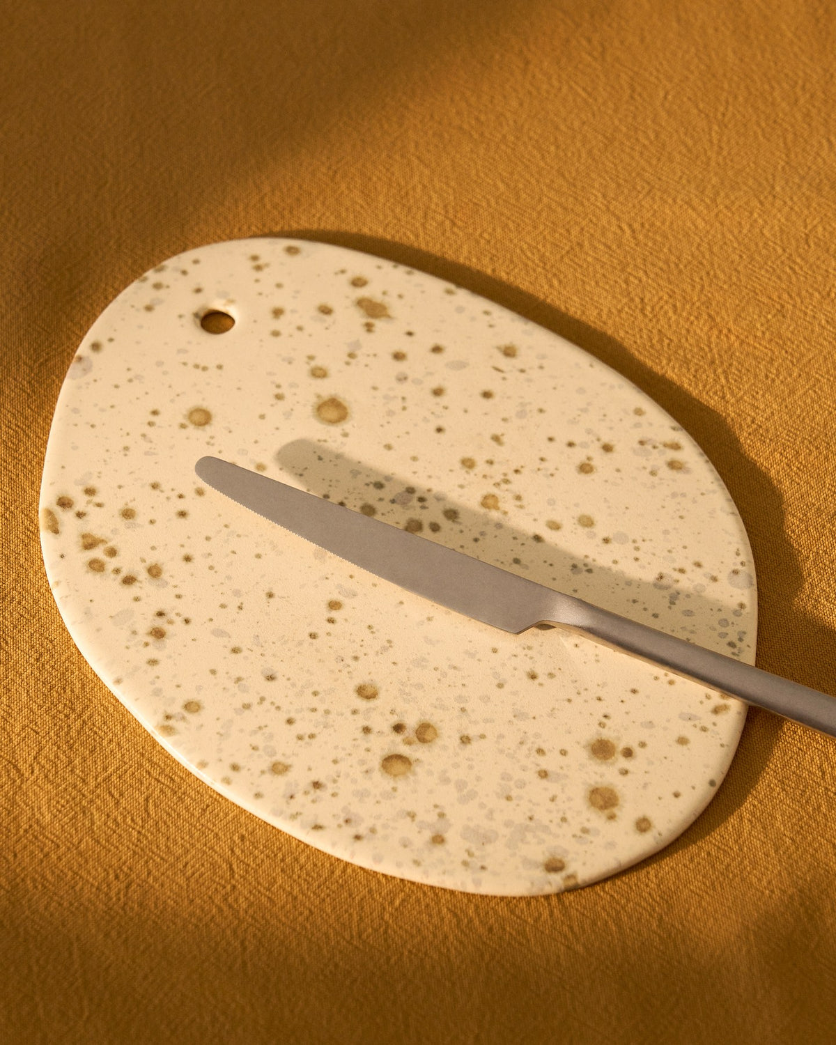 Rechteckiges Servierbrett aus weisser Keramik mit braunem gesprenkeltem Aufdruck, Kollektion Convia von Kave Home, glänzende Oberfläche.