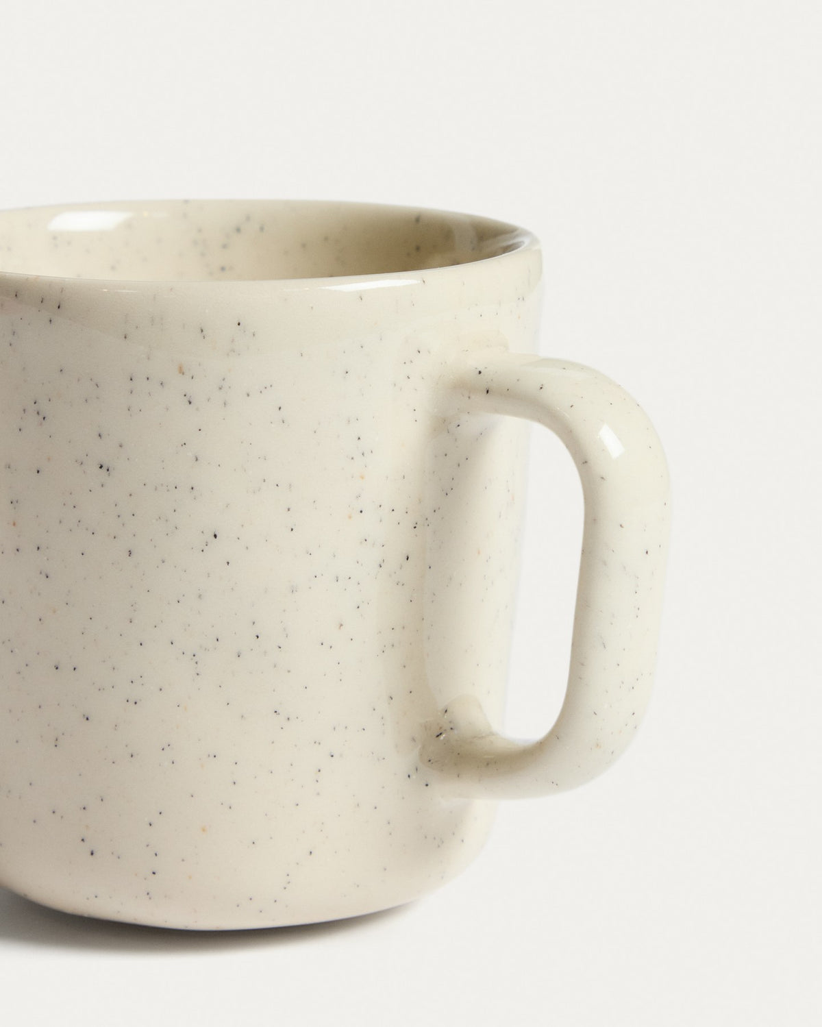Weisse Tasse Daner aus glänzender Keramik mit schlichter, runder Form und leicht beiger Färbung, fotografiert vor neutralem Hintergrund.
