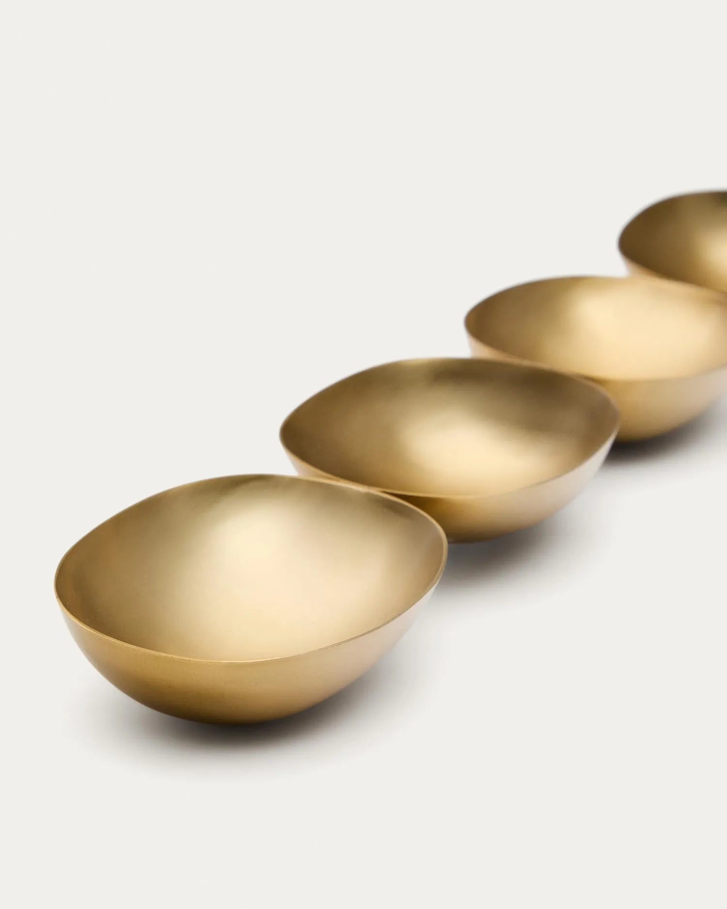 Set aus vier goldfarbenen Edelstahlschüsseln von Kave Home, perfekt für moderne Tischdekoration und stilvolle Präsentationen.