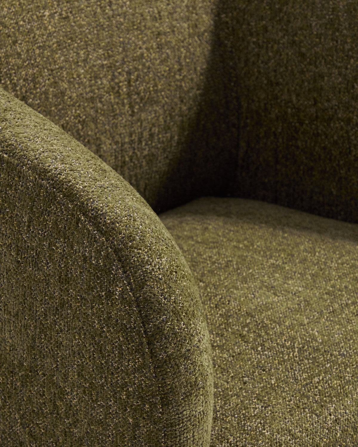 Sessel Milare von Kave Home mit olivgrünem Chenille-Bezug, abgerundeter Rückenlehne und Armlehnen sowie Kunststoffgleitern an den Beinen.