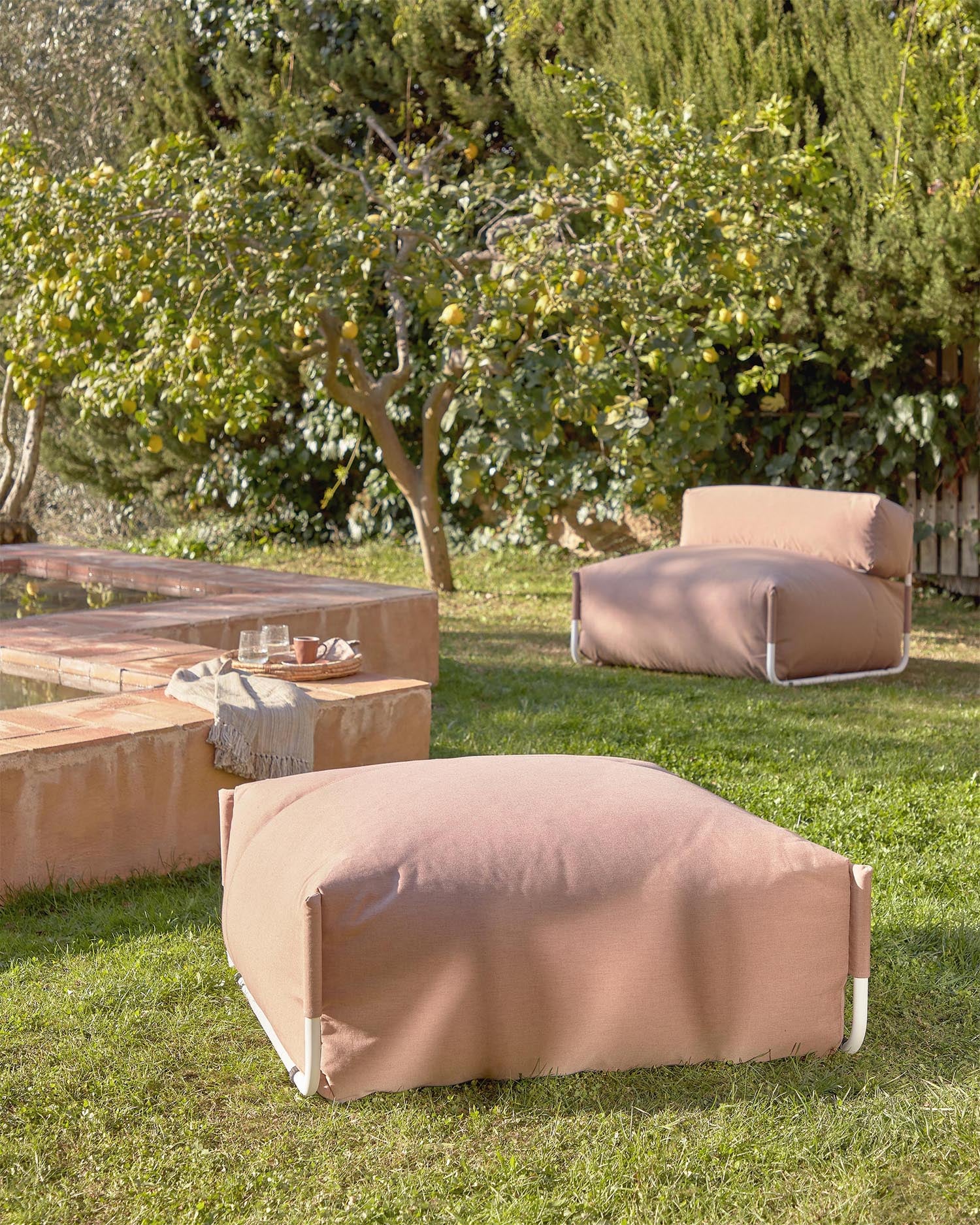 Ein stilvoller, wetterfester Pouf in Terrakotta und Weiß, ideal für flexible Outdoor-Lounges.