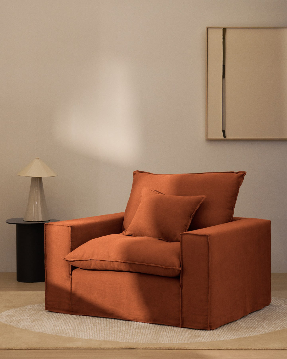 Sessel Anarela von Kave Home in Terrakotta mit abnehmbarem Leinenbezug, schwarzen Kunststoffbeinen und gepolsterter Sitzfläche, Frontalansicht.