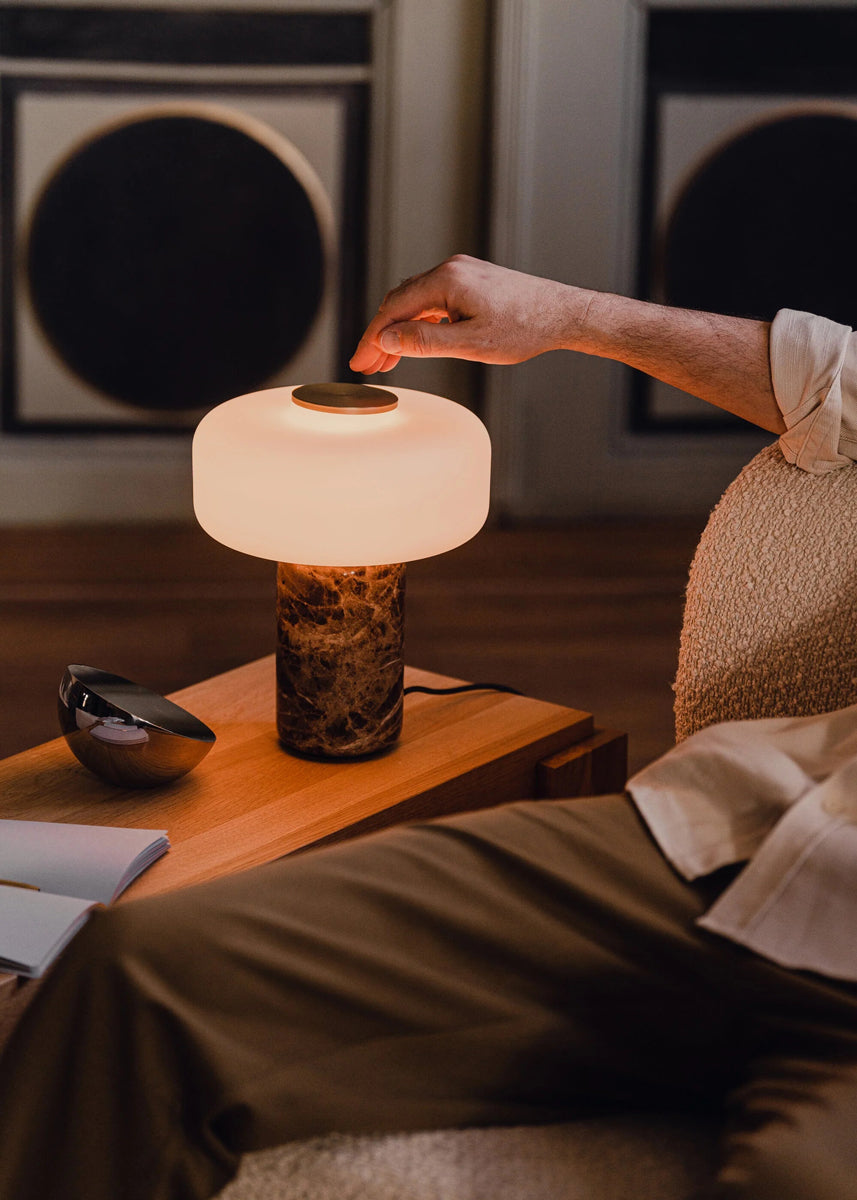 Moderne Tischleuchte Fonte FNT01 von Tamo mit zylindrischem Schirm, eleganter Holz- oder Metallbasis, sorgt für warmes Licht und stilvolle Akzente.