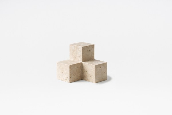 Buchstütze Tero aus Travertin in der Farbe Travertin Romano, geometrische Form mit natürlicher Maserung, auf hellem Untergrund fotografiert.