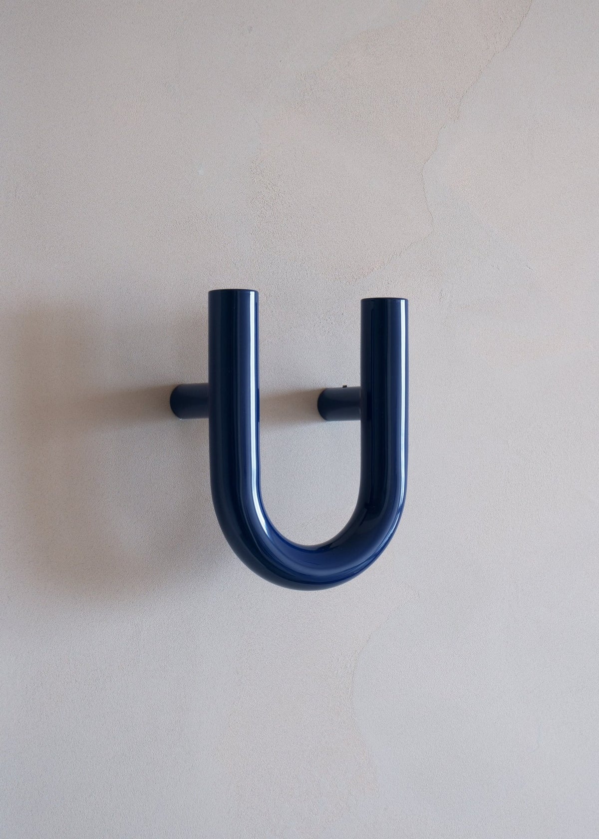 Wandhaken Une von Tamo in Kobaltblau, pulverbeschichteter Stahl, skulpturale Form, montiert an weisser Wand als Kleiderhaken