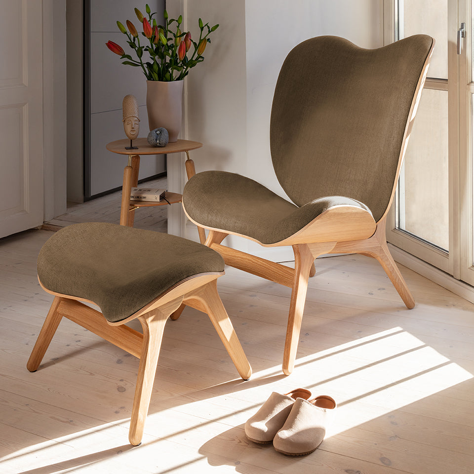 Eleganter A Conversation Piece Ottoman in warmem Sugar Brown, stilvoll inszeniert für ein modernes Wohnambiente.