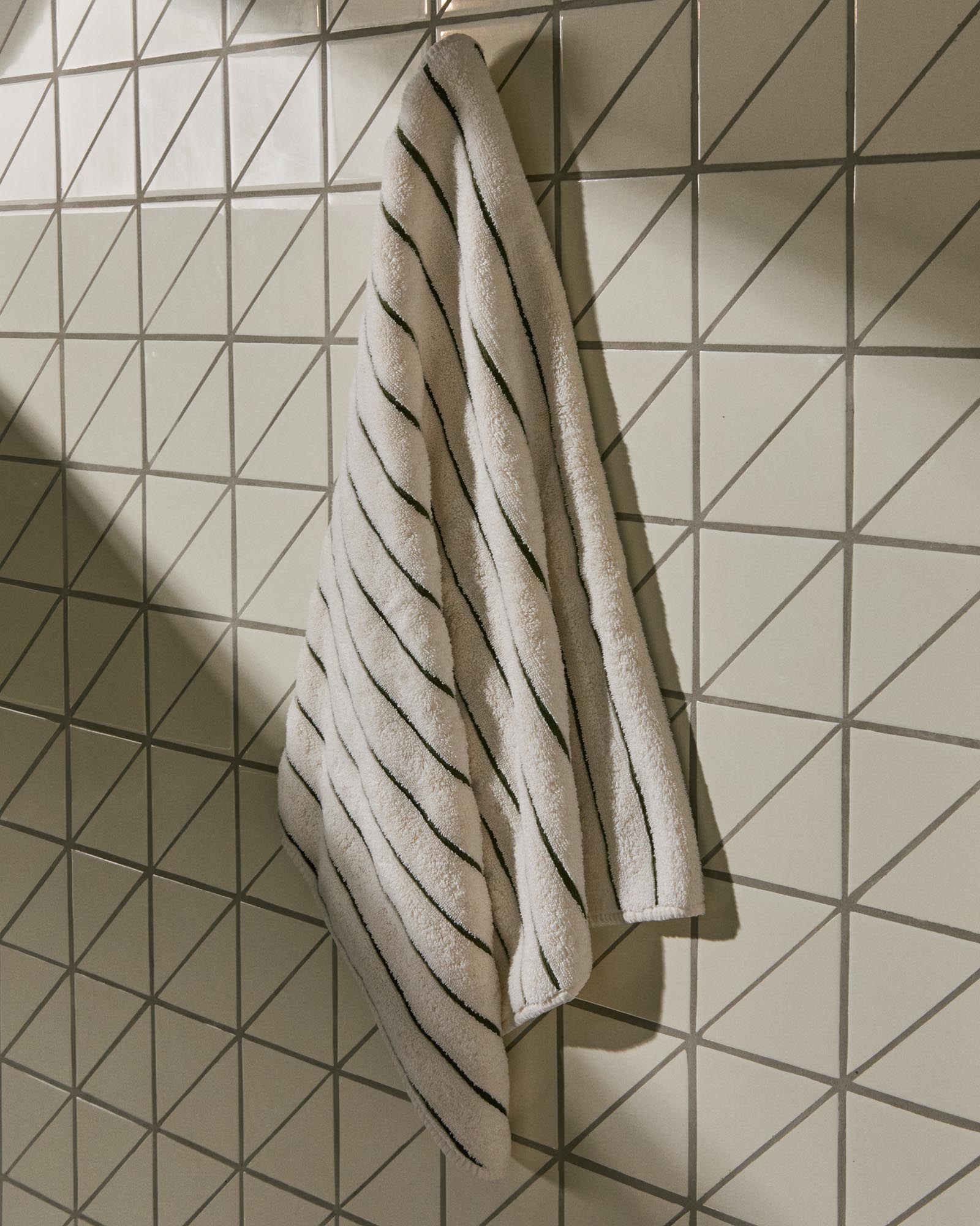 Elegantes Handtuch Dorane in sanften Grüntönen, gefertigt aus 100 % Baumwolle, ideal für stilvolle Badezimmergestaltung.