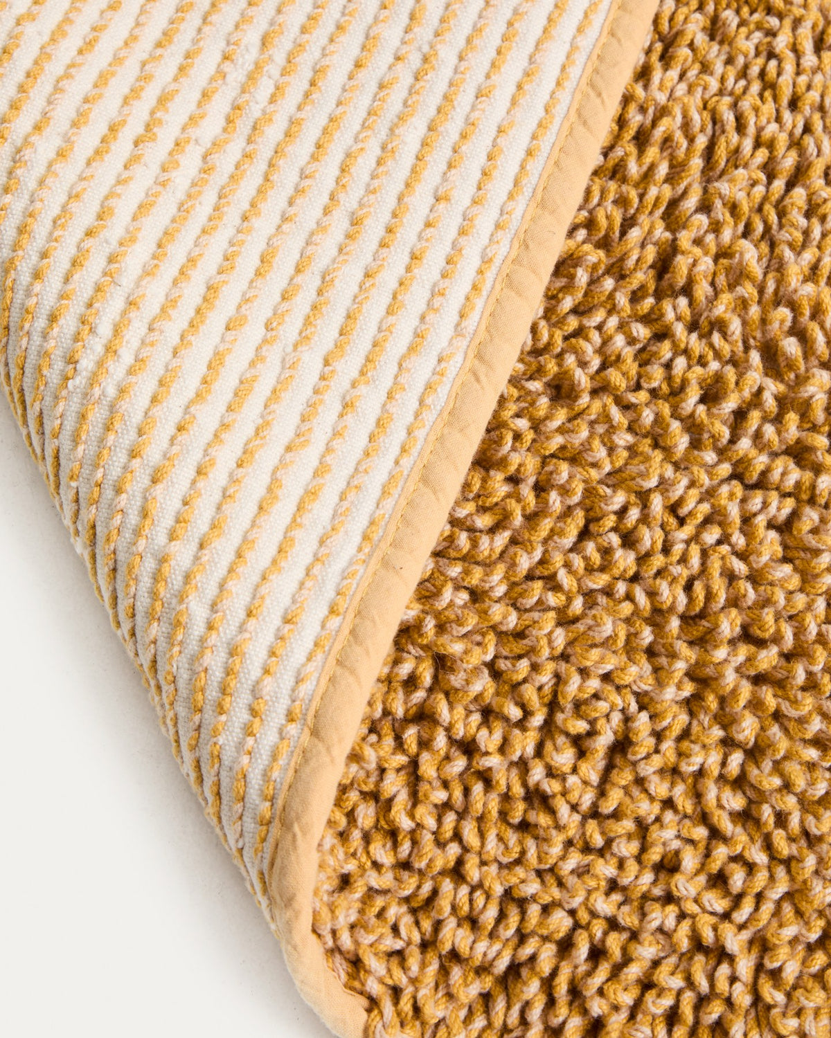 Senfgelbe Badezimmermatte Aroia von Kave Home mit Bouclé-Melange-Struktur in rechteckiger Form, Grösse 50 x 70 cm, auf Boden liegend.