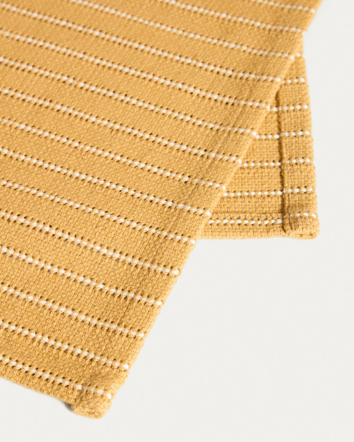 Zwei senfgelbe Tischsets aus Baumwolle mit eingewebtem Jacquard-Muster, rechteckige Form, auf einem Tisch platziert.