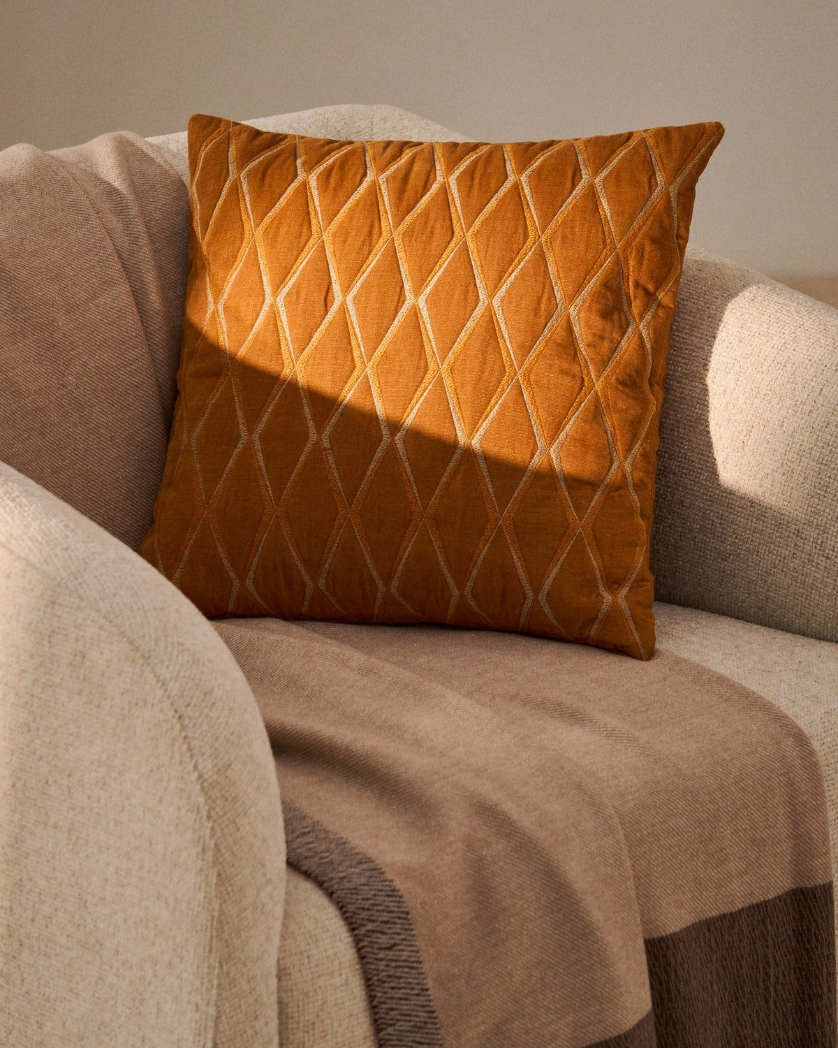 Foto zeigt quadratischen Kissenbezug aus orangefarbenem Mikrosamt mit geometrischer Stickerei, Grösse 45 x 45 cm, von Kave Home.