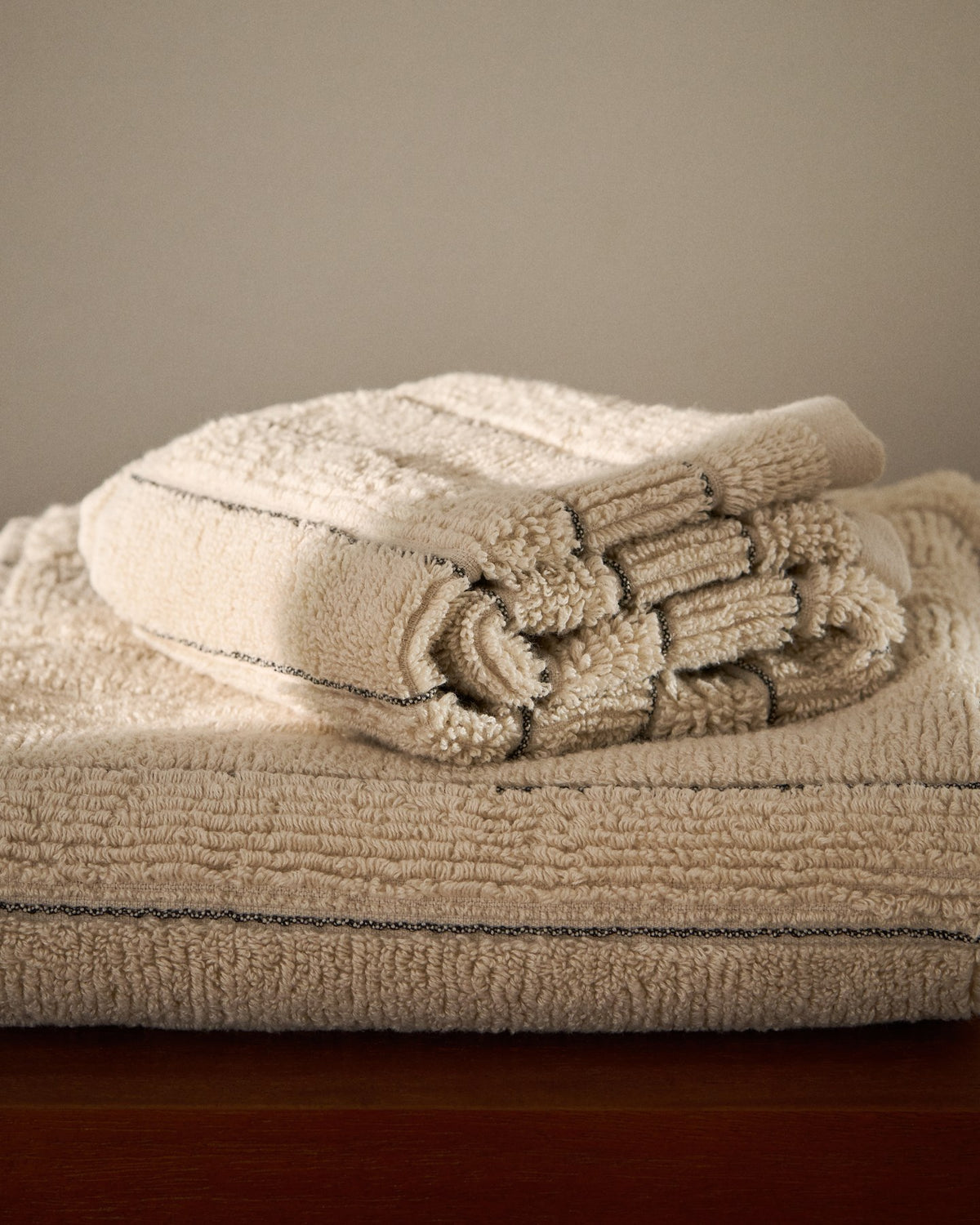 Beiges Toilettenhandtuch aus 100% Baumwolle mit Jacquard-Streifenmuster, Grösse 30 x 50 cm, gefaltet auf hellem Untergrund liegend.