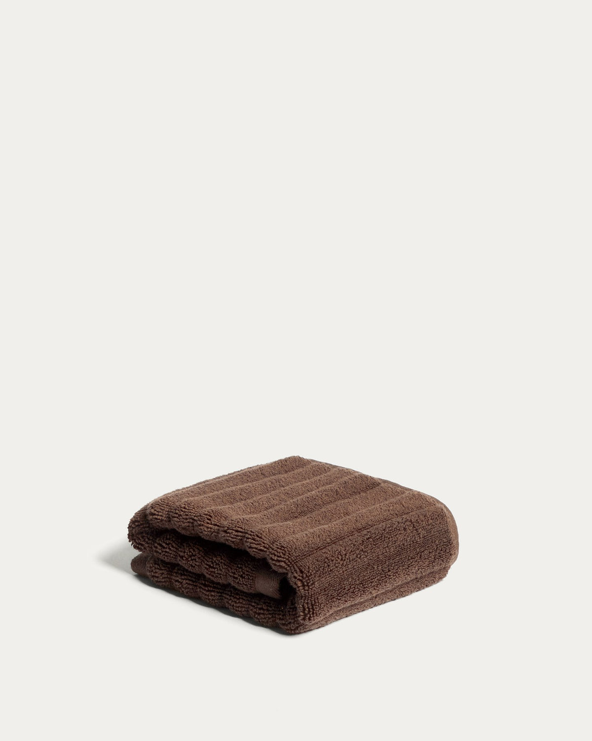 Granatrotes Toilettenhandtuch aus 100 % Baumwolle mit welliger Struktur, Grösse 30 x 50 cm, liegt gefaltet auf hellem Untergrund.