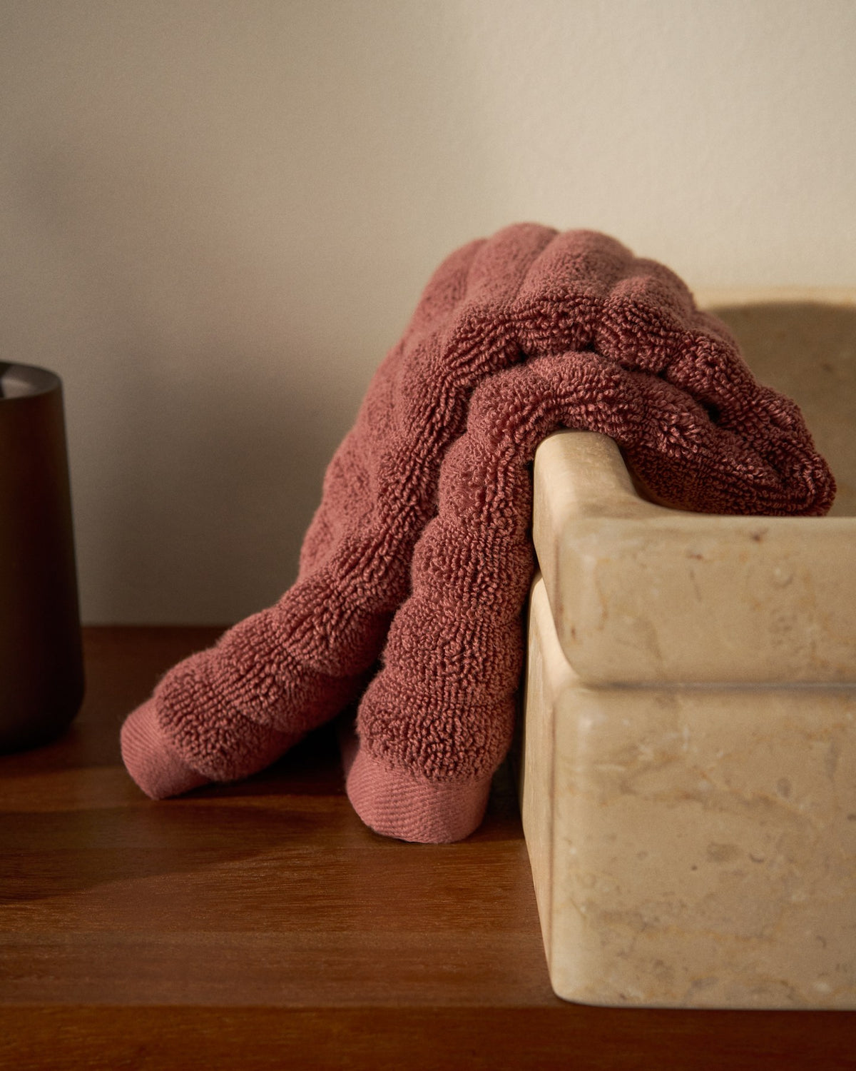 Granatrotes Toilettenhandtuch aus 100 % Baumwolle mit welliger Struktur, Grösse 30 x 50 cm, liegt gefaltet auf hellem Untergrund.