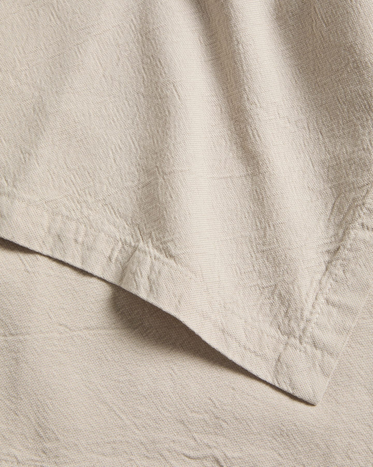 Zwei Tischsets aus Baumwolle mit steingrauem Washed-Finish und Leinen-Look, rechteckige Form, auf einem Tisch drapiert.