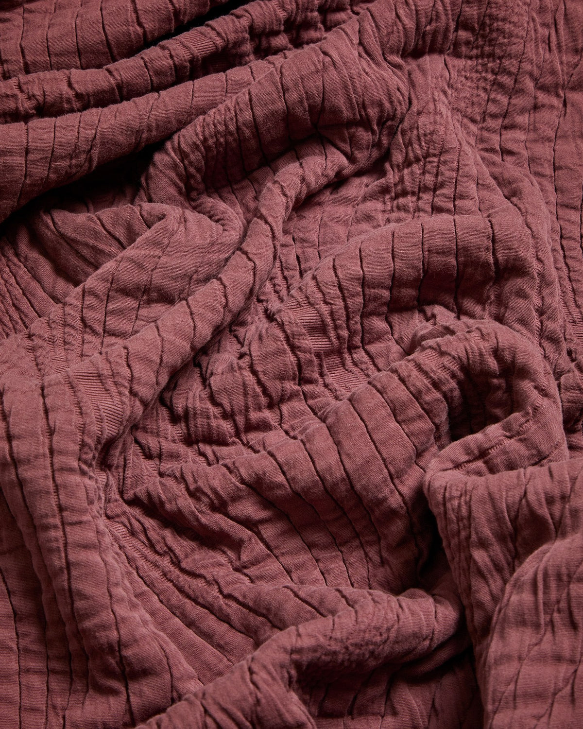 Tagesdecke Sarula aus 100% Baumwolle mit Jacquard-Wellenmuster, cremefarben, gefaltet auf einem Bett liegend, Masse 180 x 260 cm.