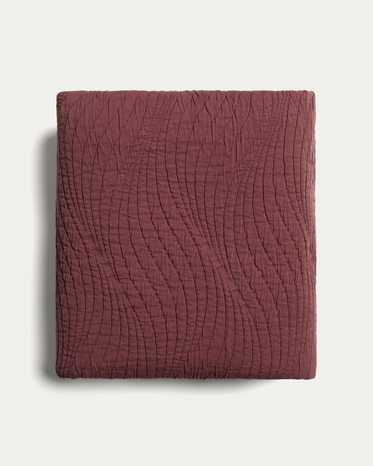 Weinrote Tagesdecke Sarula aus 100% Baumwolle mit Jacquard-Wellenmuster, ausgebreitet auf einem Bett, Grösse 240 x 260 cm.